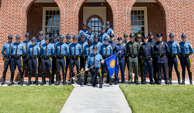 new officers group photo in front of the police academy